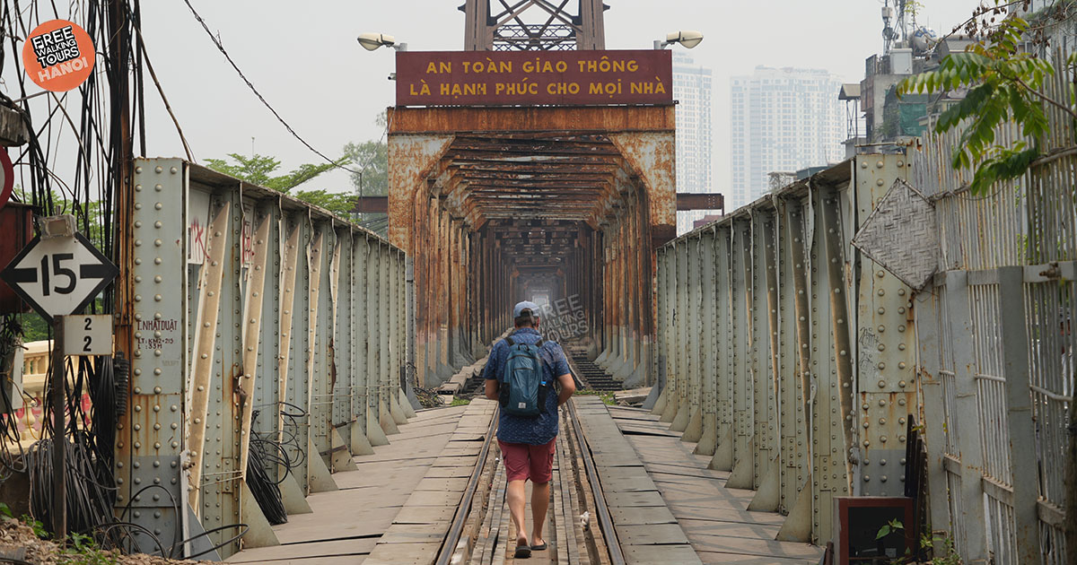 Travelers from Europe and the US walking with locals across Hanoi’s historic Long Bien Bridge